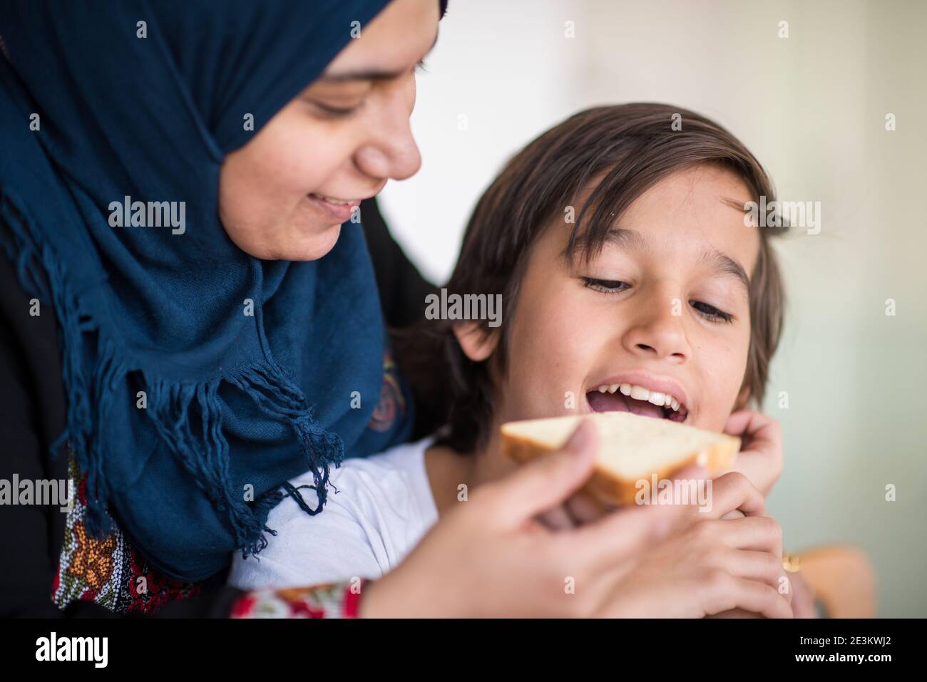 Donna musulmana tradizionale con figlio in cucina Foto Stock