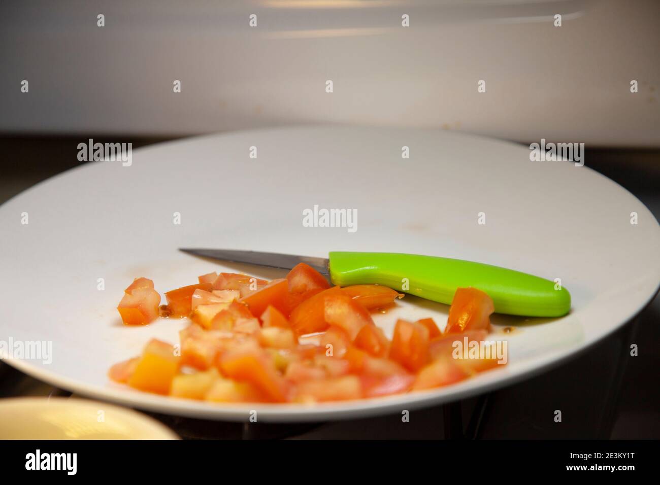 I pomodori tagliati a dadini su un piatto bianco con un coltello da paring Foto Stock