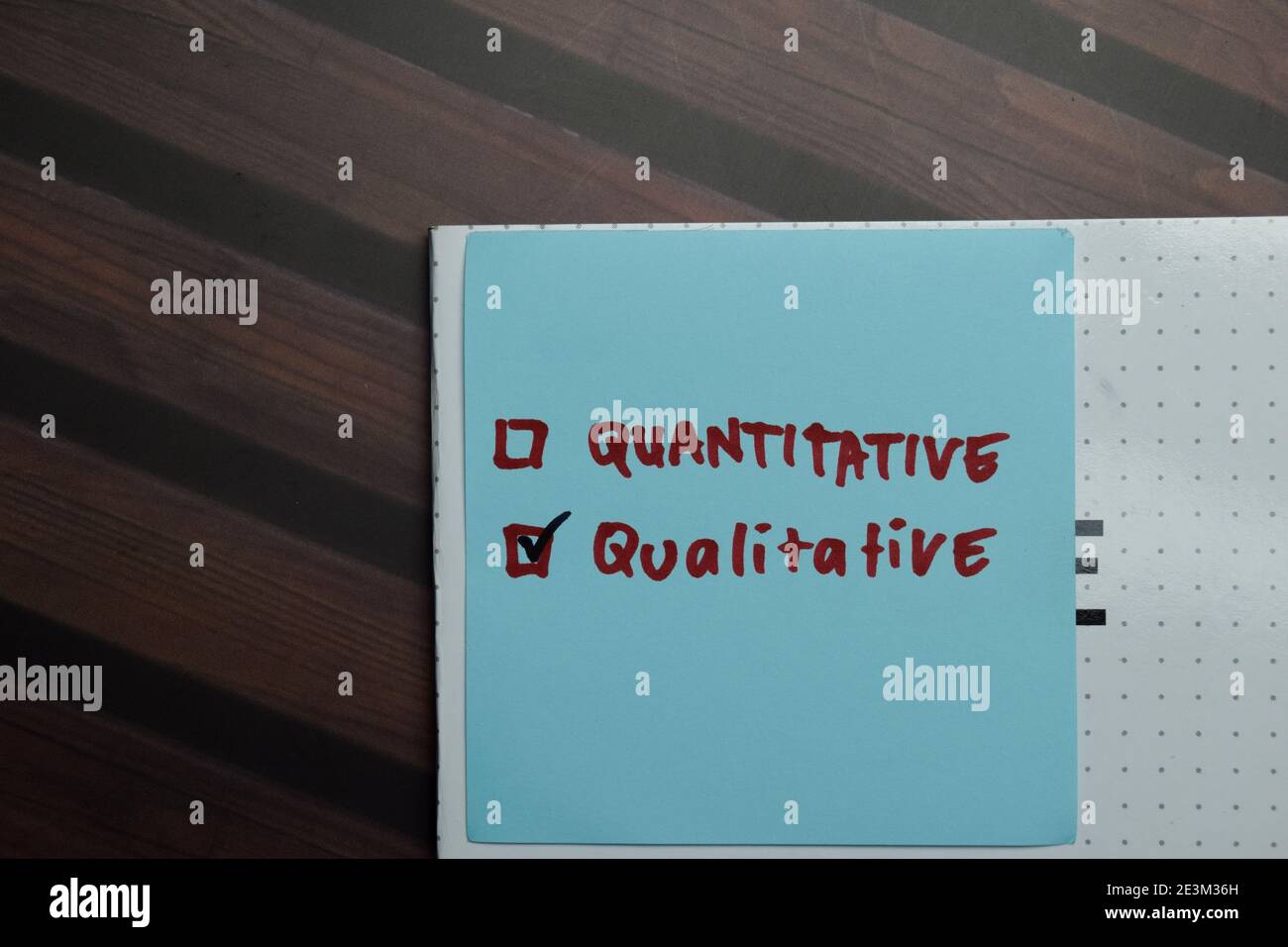 Scrittura quantitativa e qualitativa su note appiccicose e supportata da servizi aggiuntivi scrivono su note appiccicose isolate su tavola di legno. Foto Stock