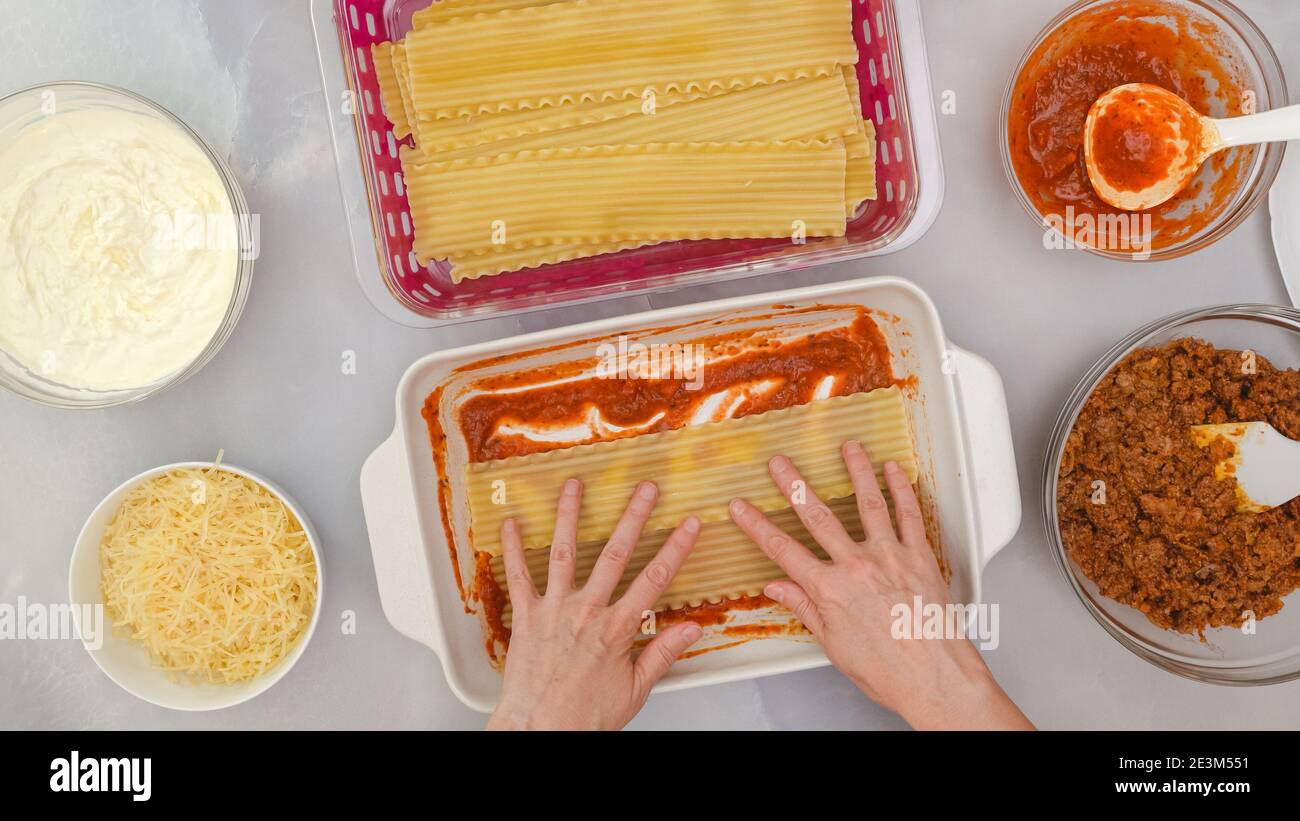 Lasagna di manzo, ricetta passo dopo passo. Assemblare la lasagna. Strato di tagliatelle di lasagna. Mani donna, piatto Foto Stock