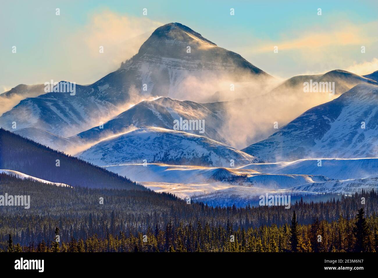 Un paesaggio invernale delle montagne rocciose canadesi con venti soffici in luce tramonto nella campagna Alberta Canada. Foto Stock