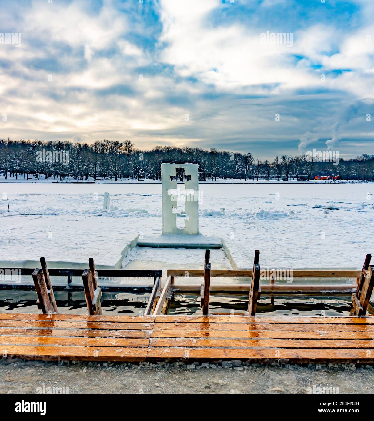 Scultura di ghiaccio a forma di croce accanto a. il fonte di immersione battesimale Foto Stock