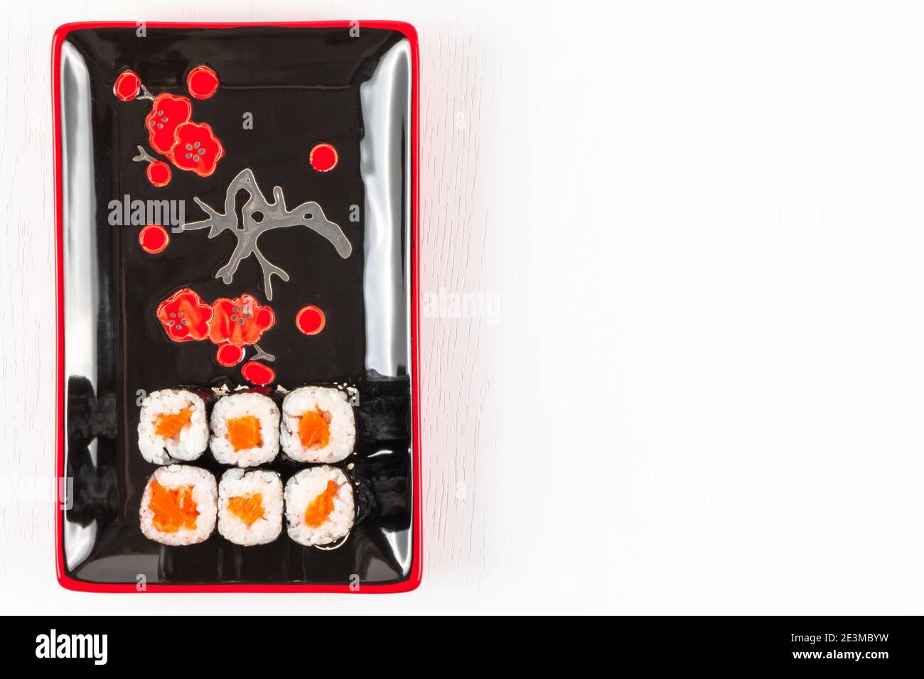 involtini appetitosi freschi con salmone in nori alghe in piatti nero-rosso su un piatto bianco. vista dall'alto Foto Stock