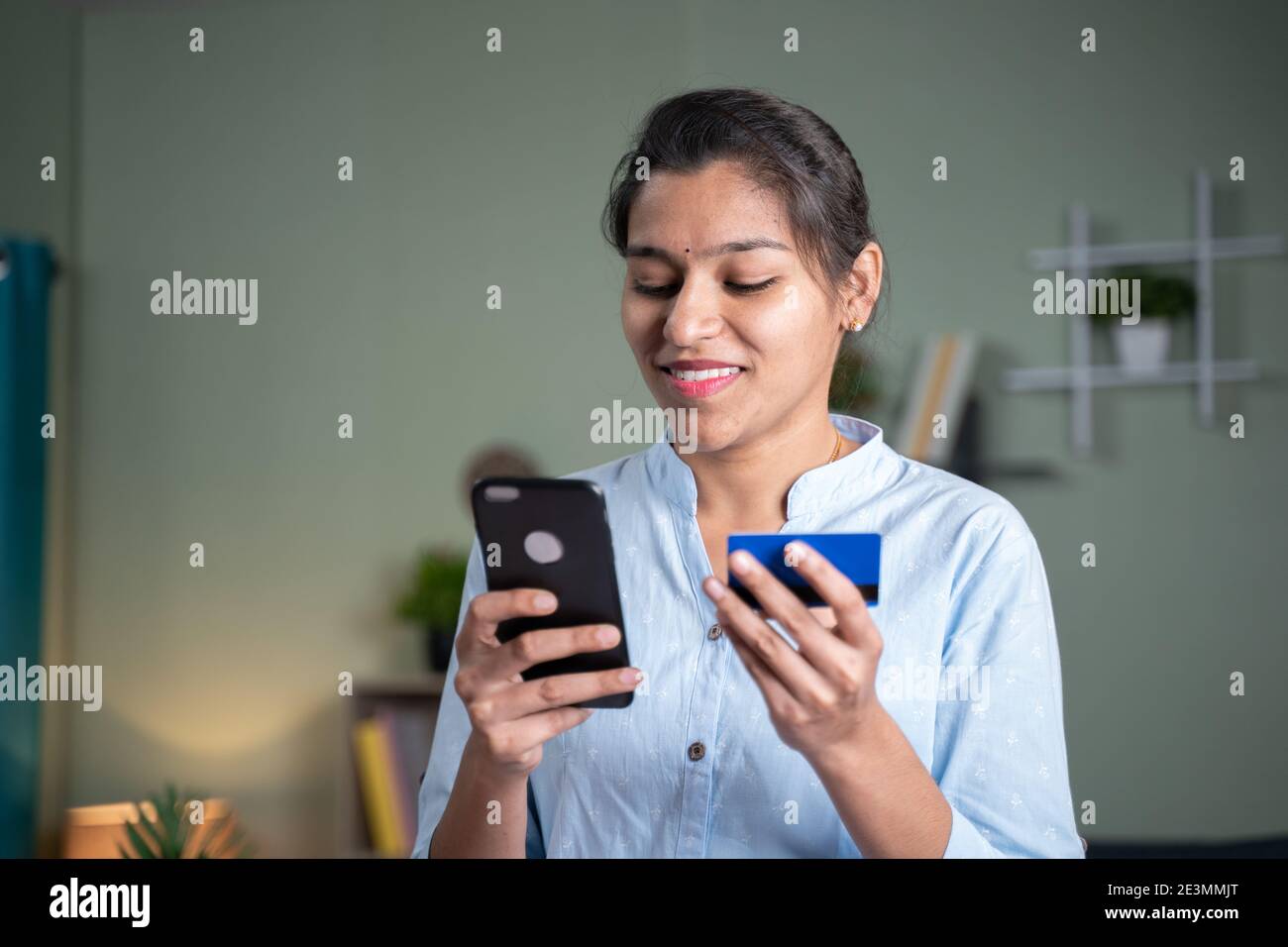 Giovane donna indiana di affari che inserisce i dettagli della carta sul telefono cellulare per l'acquisto online - concetto di pagamento digitale per lo shopping, Internet banking e. Foto Stock
