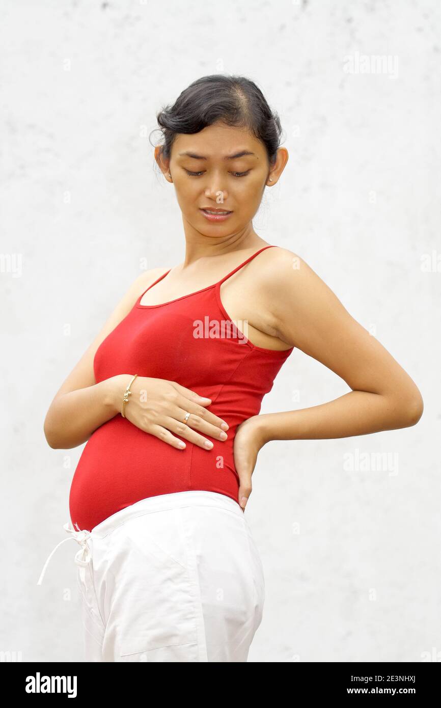 Donna incinta di etnia asiatica sente dolori alla schiena o vita Foto Stock