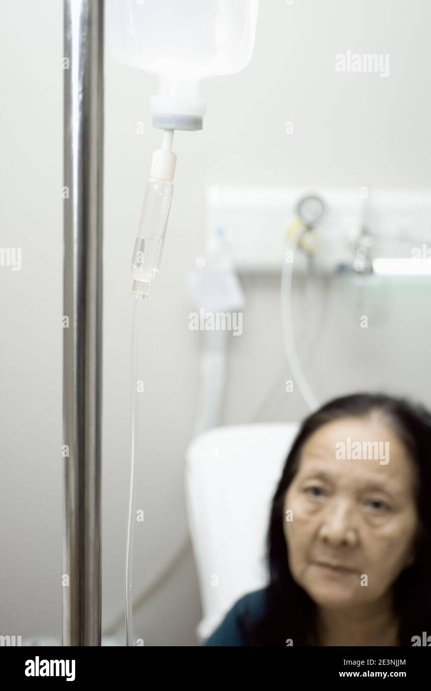 Asian vecchia donna a ottenere l'infusione durante il trattamento di ricovero in ospedale Foto Stock