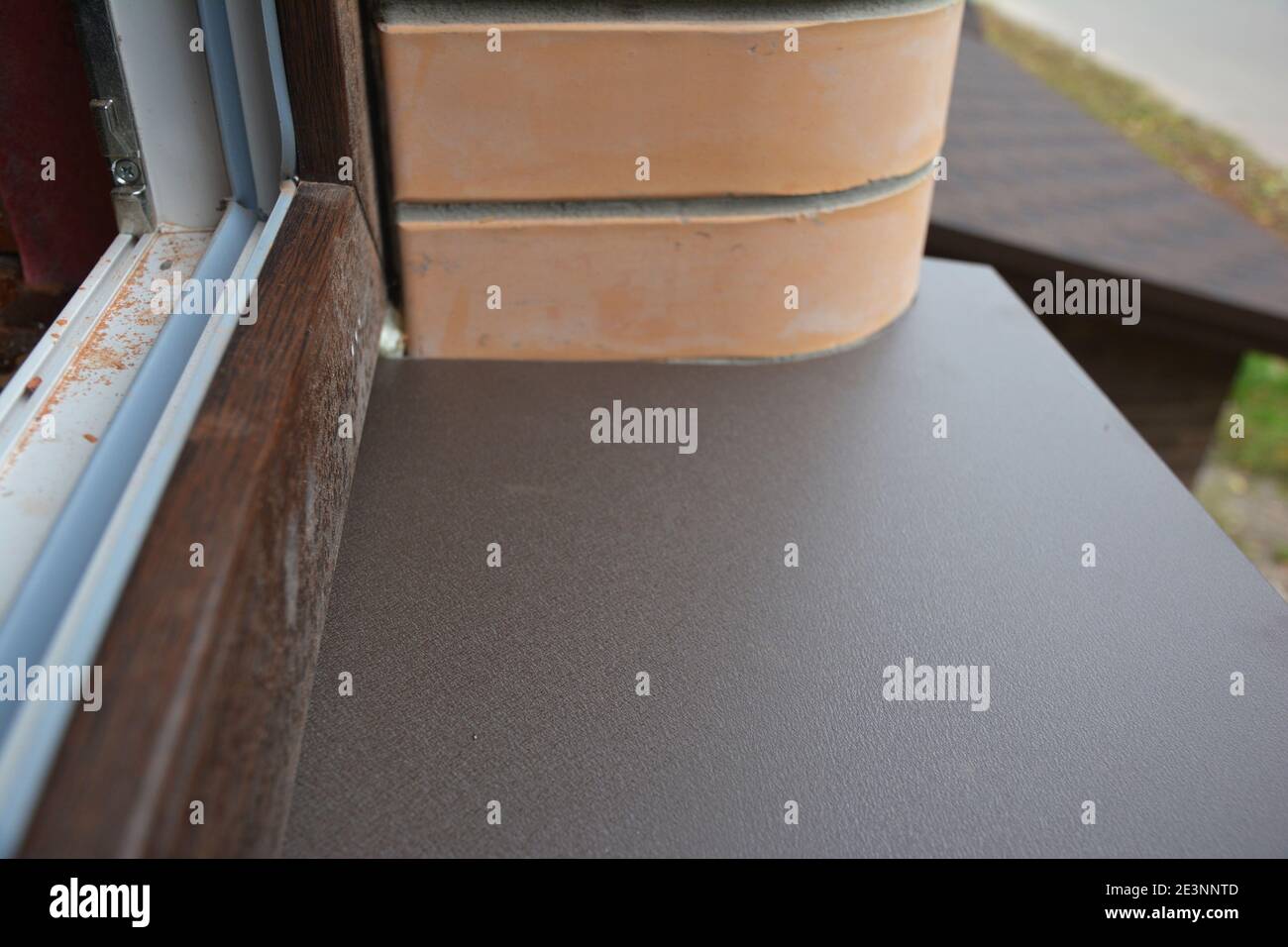 Un primo piano sull'installazione di finestre in plastica upvc di colore bianco all'interno e marrone all'esterno con un telaio per finestre e una soglia esterna installati. Foto Stock