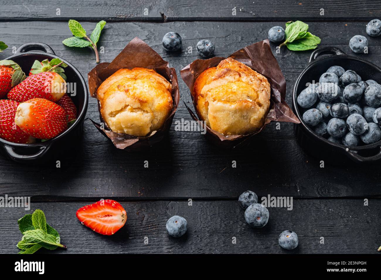 Muffin ai mirtilli con berrie fresca, su sfondo di legno nero Foto Stock