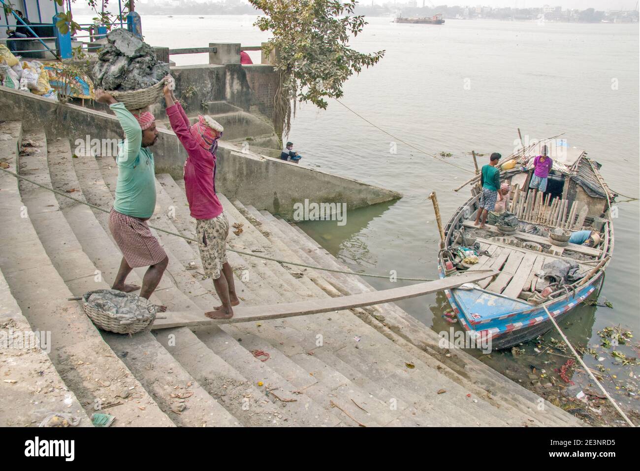 Il limo per la produzione di idoli viene scaricato da una barca a Kumortuli ghat. Il limo ideale per la produzione di idoli è il terreno fluviale che viene prelevato dal kolaghat. Foto Stock