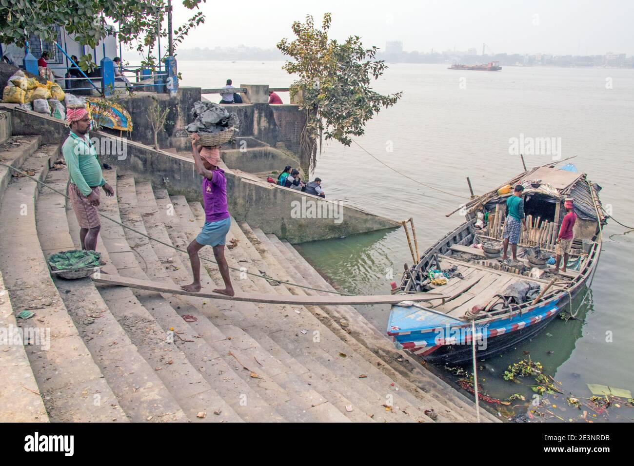 Il limo per la produzione di idoli viene scaricato da una barca a Kumortuli ghat. Il limo ideale per la produzione di idoli è il terreno fluviale che viene prelevato dal kolaghat. Foto Stock