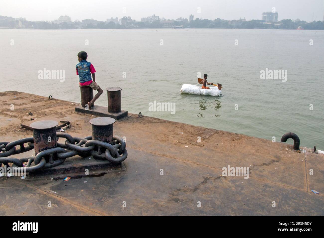Un bambino viaggia in zattera sul fiume Gange a Kolkata. Viaggiare su questa zattera è solo una parte dell'infanzia. Foto Stock