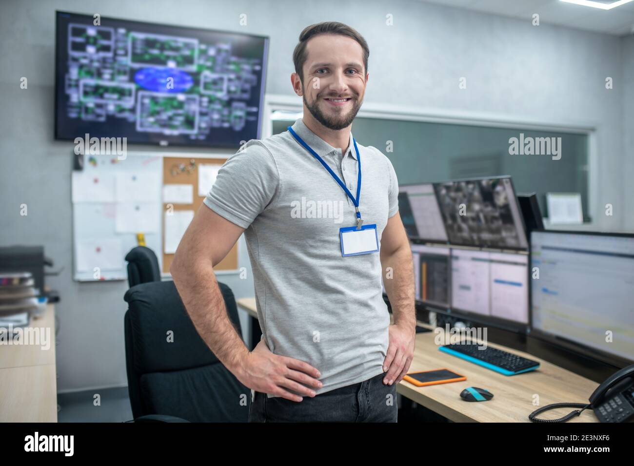 Uomo gioioso in piedi vicino al lavoro mettere le mani sulla cintura Foto Stock