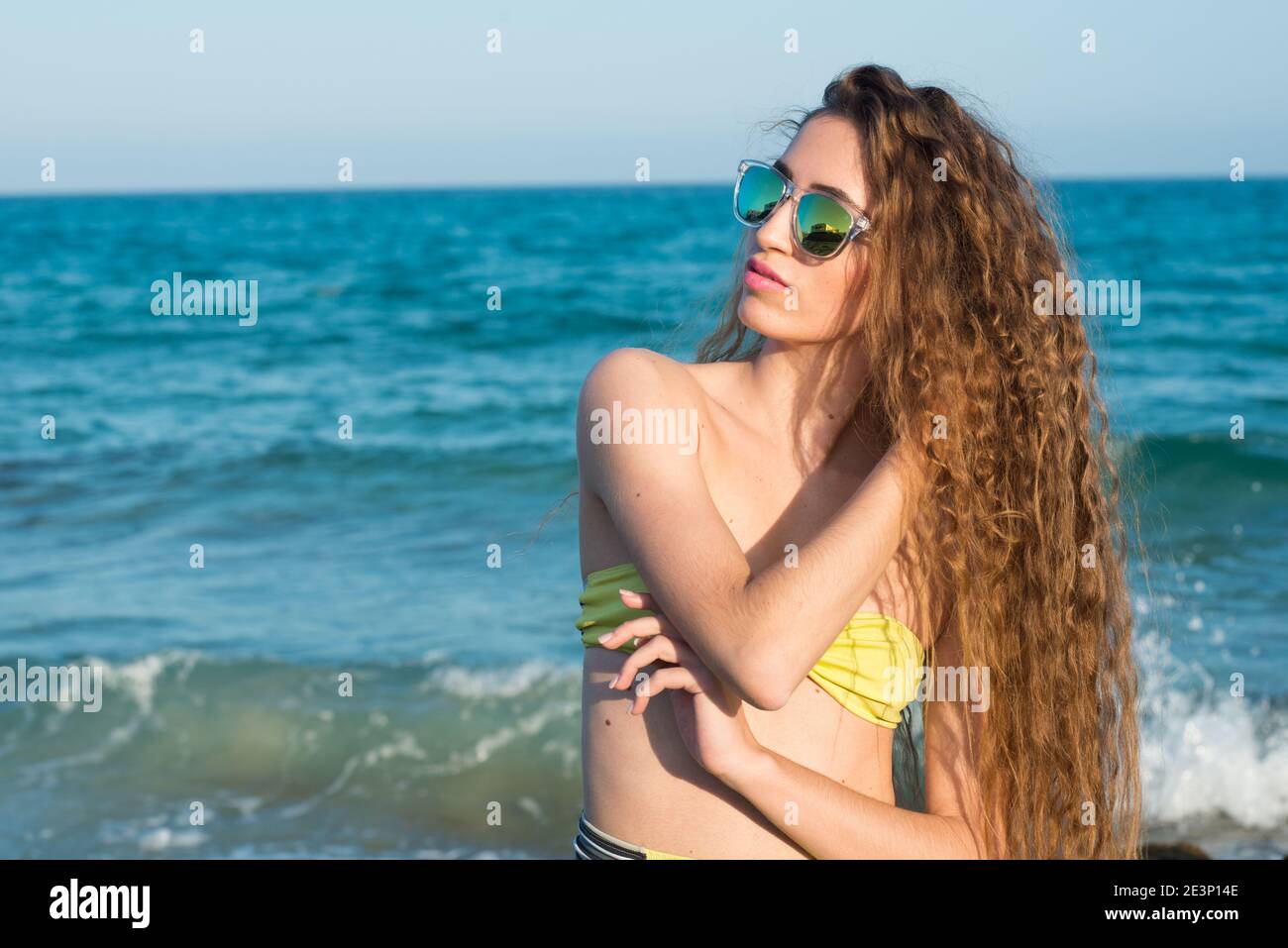 donna bionda con lunghi capelli ricci godendo il mare dentro primavera o estate Foto Stock