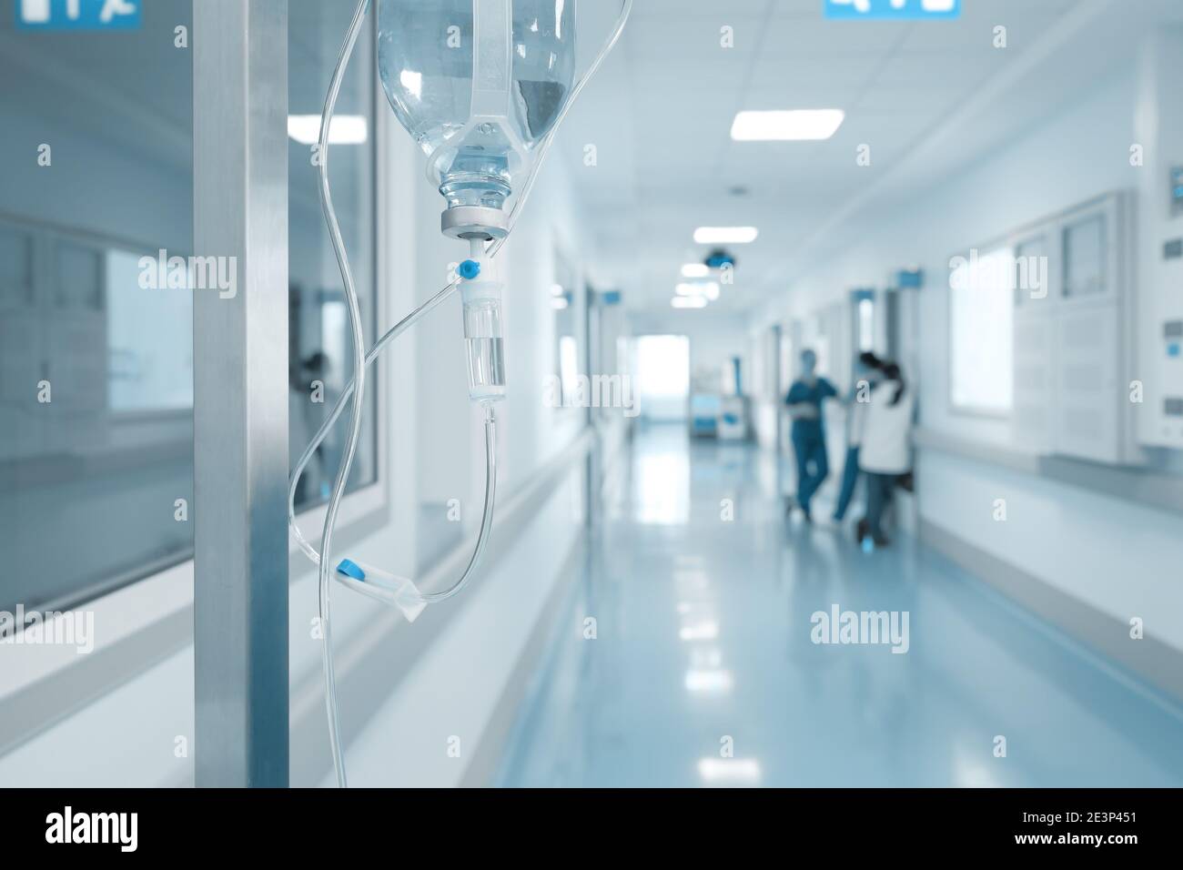 Gocciolamento endovenoso sul rack sullo sfondo di infermieri parlanti nel corridoio ospedaliero. Foto Stock