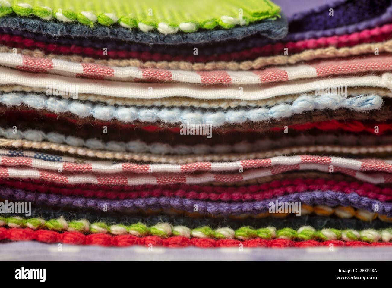 Pile colorate di diversi tessuti e tovaglie impilate sulla parte superiore l'uno dell'altro Foto Stock