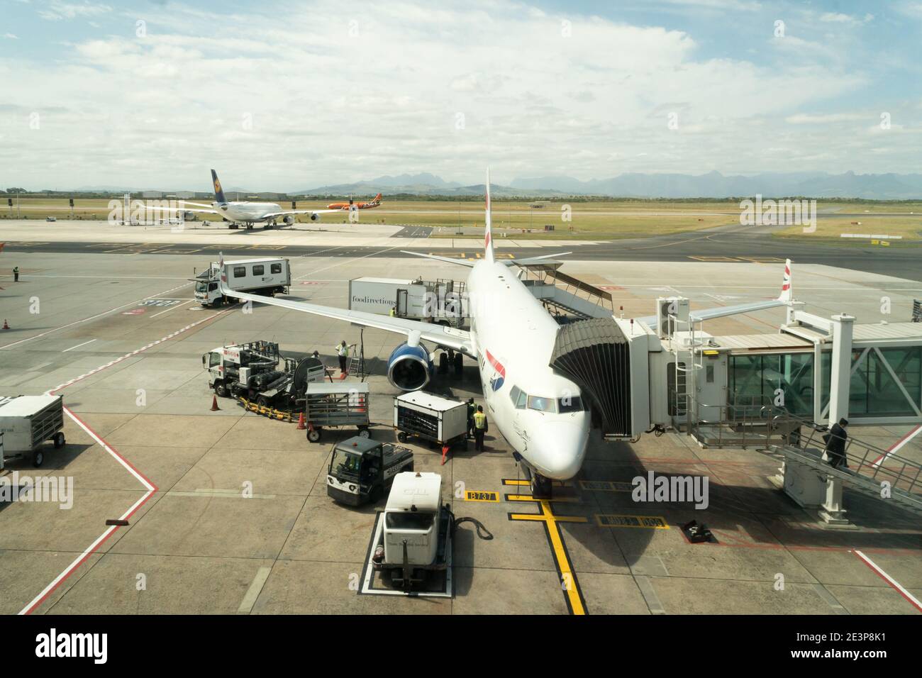 Volo della British Airways Comair presso un terminal passeggeri caricato per un volo nazionale con veicoli e dipendenti che lavorano sul asfalto Foto Stock