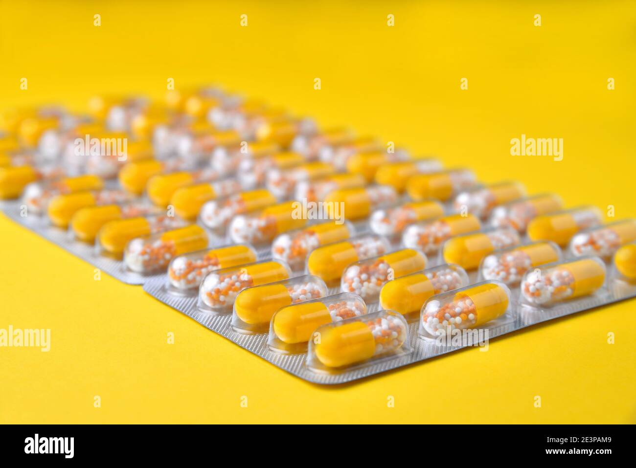 Capsule in blister. Compresse mediche, vitamine in un granulo, in capsule gialle su uno sfondo giallo. Sfocatura come idea creativa dell'autore, vicino Foto Stock