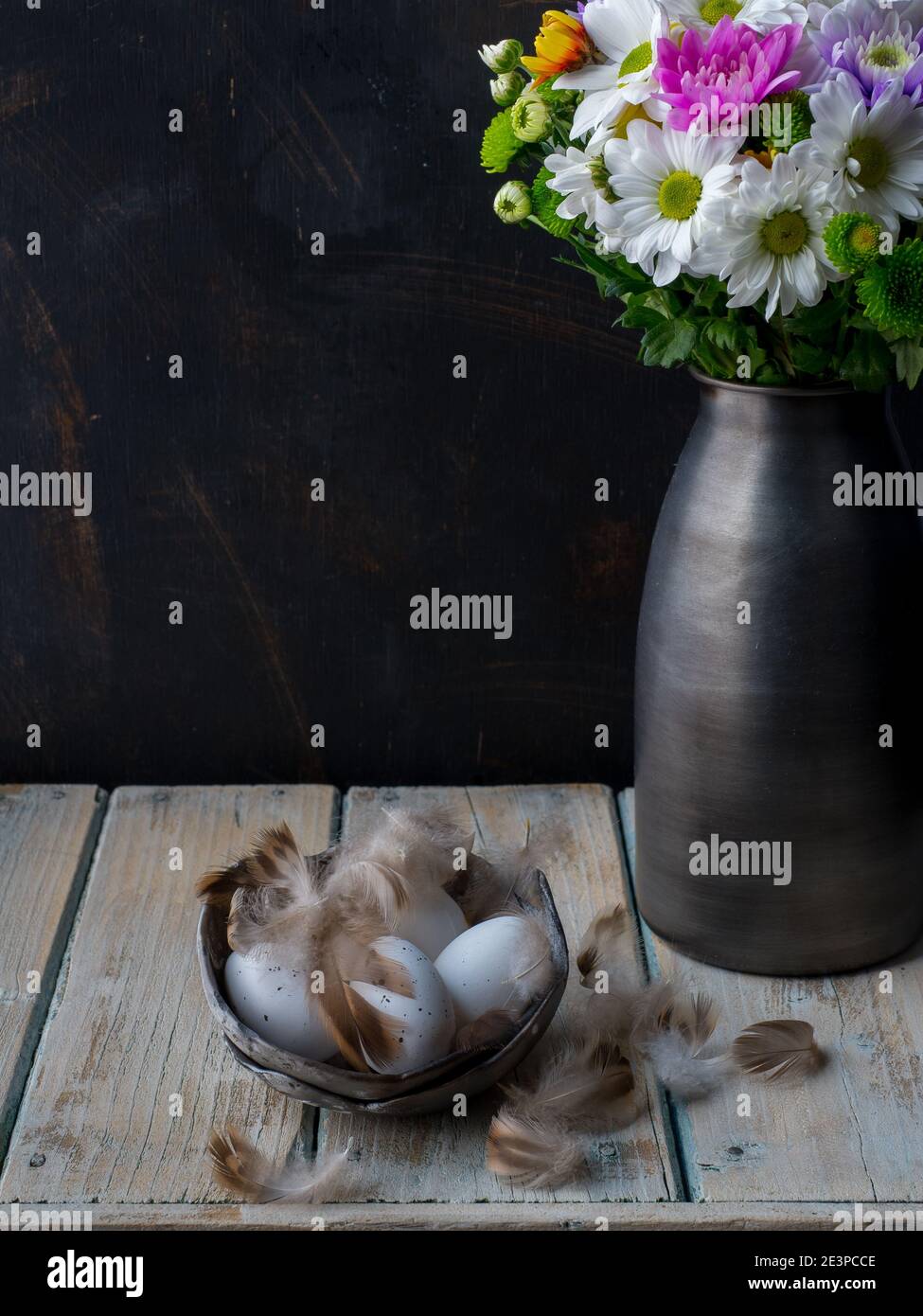Vaso con bouquet colorato di fiori in fiore e uova decorative con piume su  tavolo di legno. Spazio di copia. Buio e moody Foto stock - Alamy