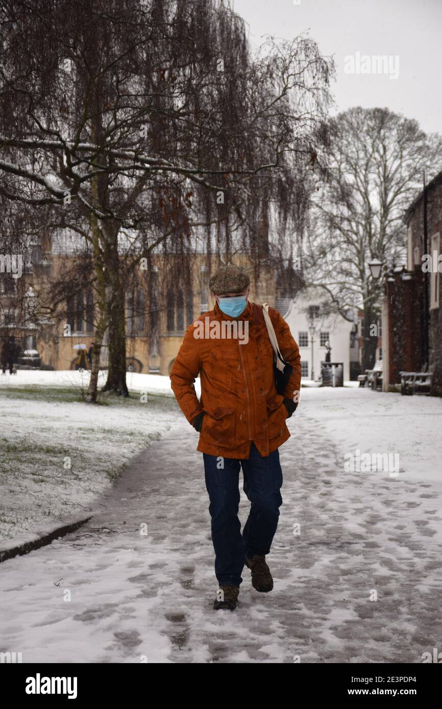 Uomo che indossa la maschera durante il blocco di Coronavirus 3, a piedi attraverso la Cattedrale chiudere nella neve, Norwich UK 2021 gennaio. Posato dal modello Foto Stock