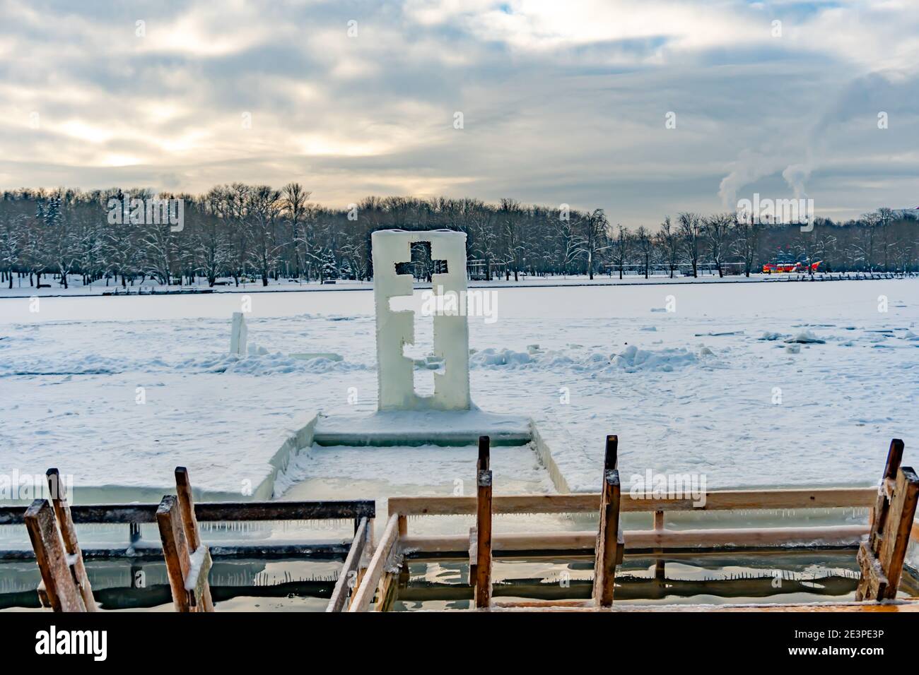 Scultura di ghiaccio a forma di croce accanto a. il fonte di immersione battesimale Foto Stock