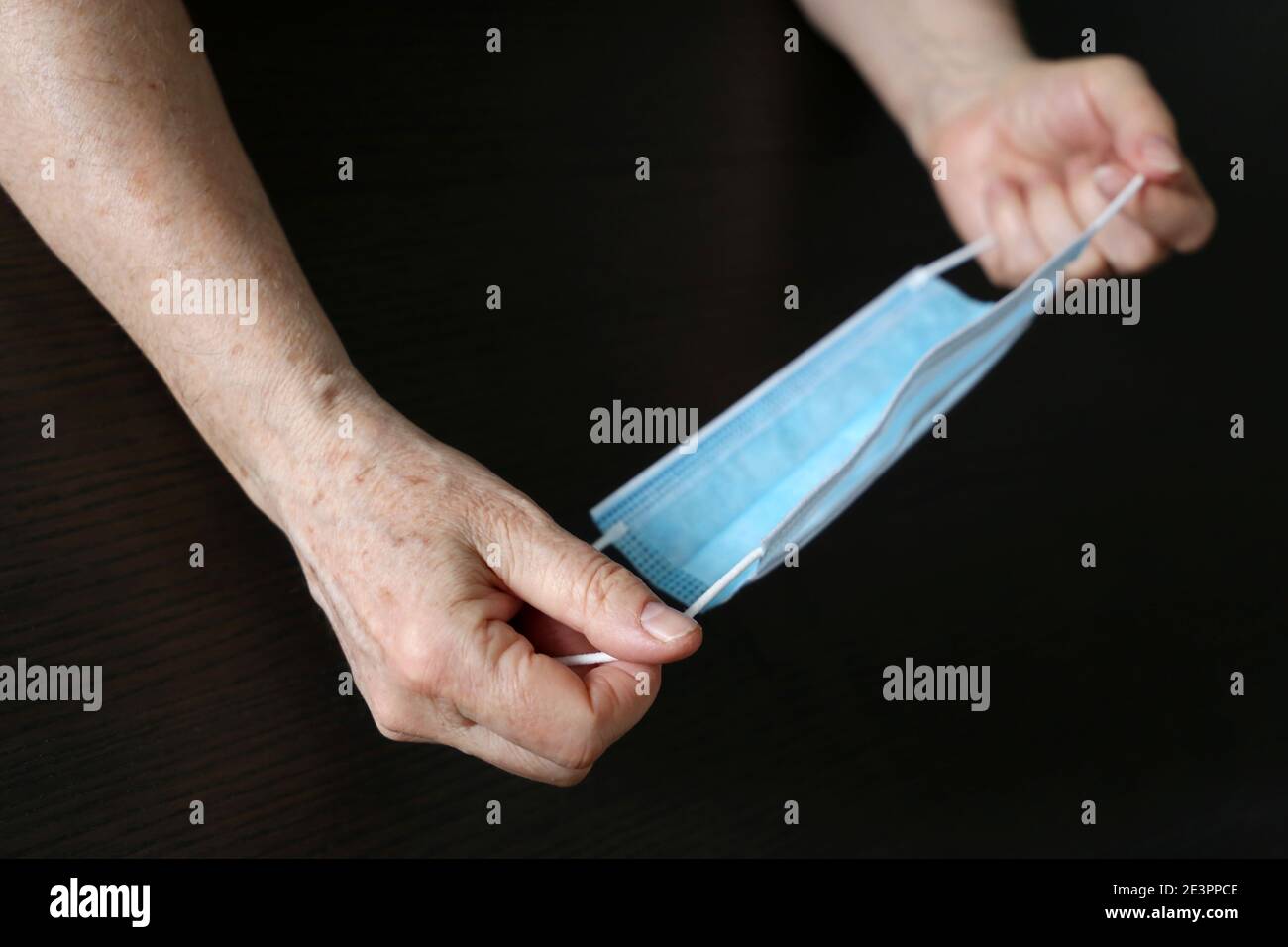 Donna anziana con maschera medica in mani rughe. Protezione del coronavirus per gli anziani Foto Stock