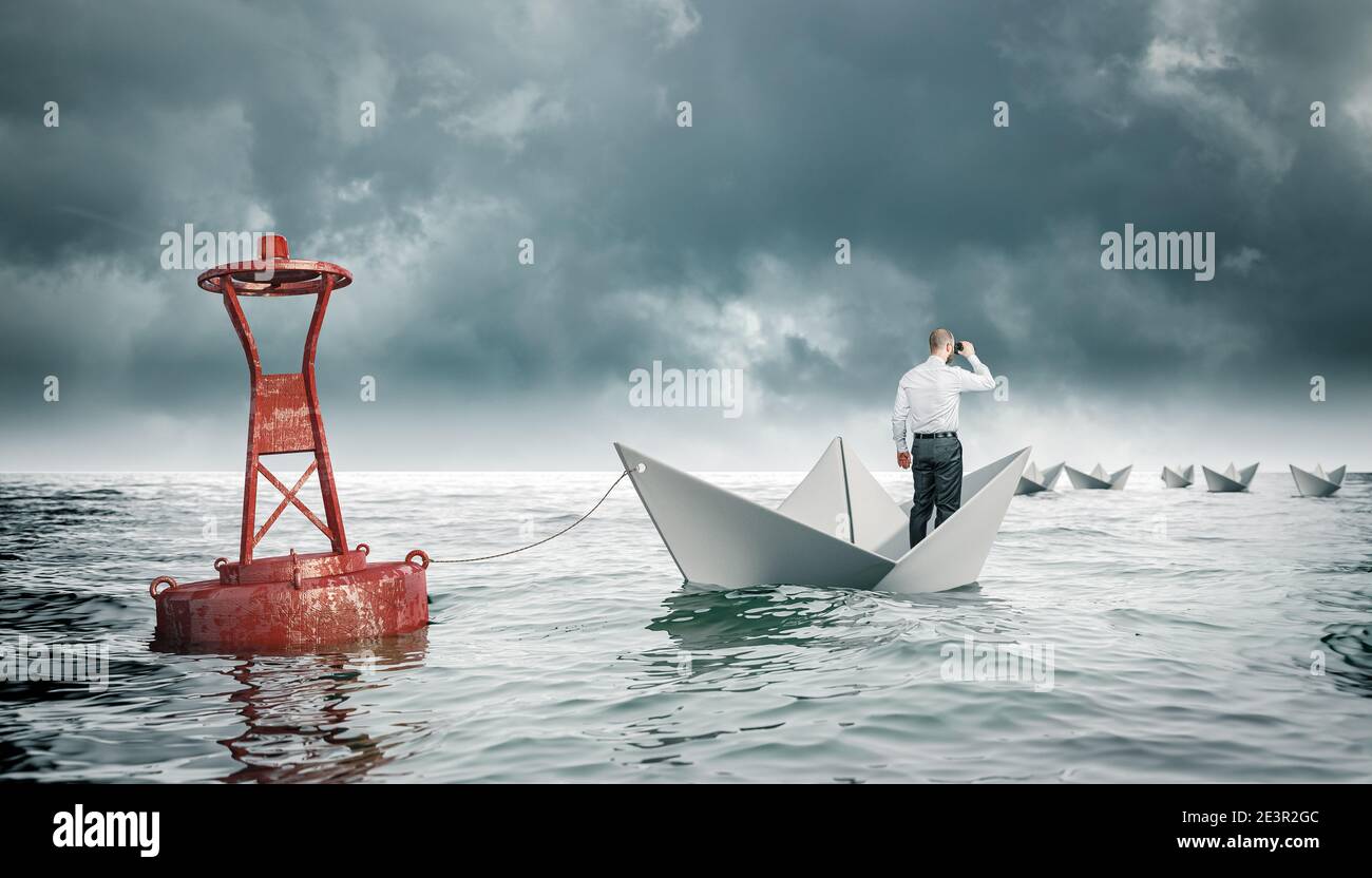 uomo con binocolo su barca di carta legato ad una boa. barche che vai via. concetto di aspirazione e avversità. Foto Stock