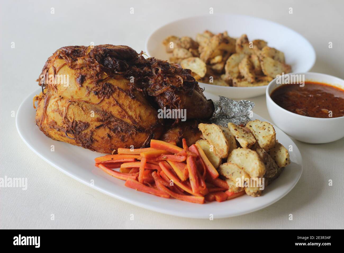 Arrosto di pollo intero con zeppe di patate e carote saltate preparate per occasioni speciali come Natale, Pasqua e altre feste Foto Stock