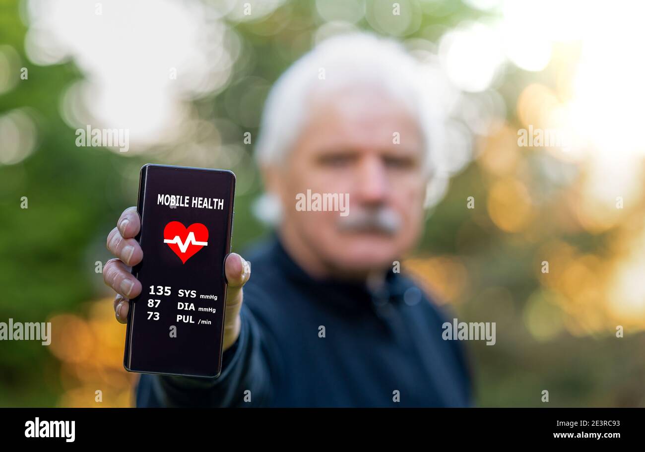 Senior Citizen che mostra un'applicazione per la salute mobile sullo smartphone, che indica la pressione sanguigna. Foto Stock