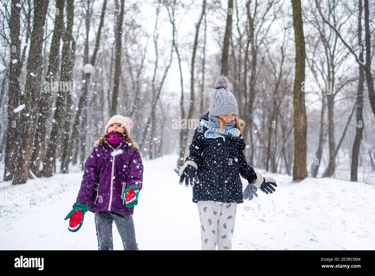 I bambini gettano la neve nell'aria e si godono un freddo giorno invernale Foto Stock