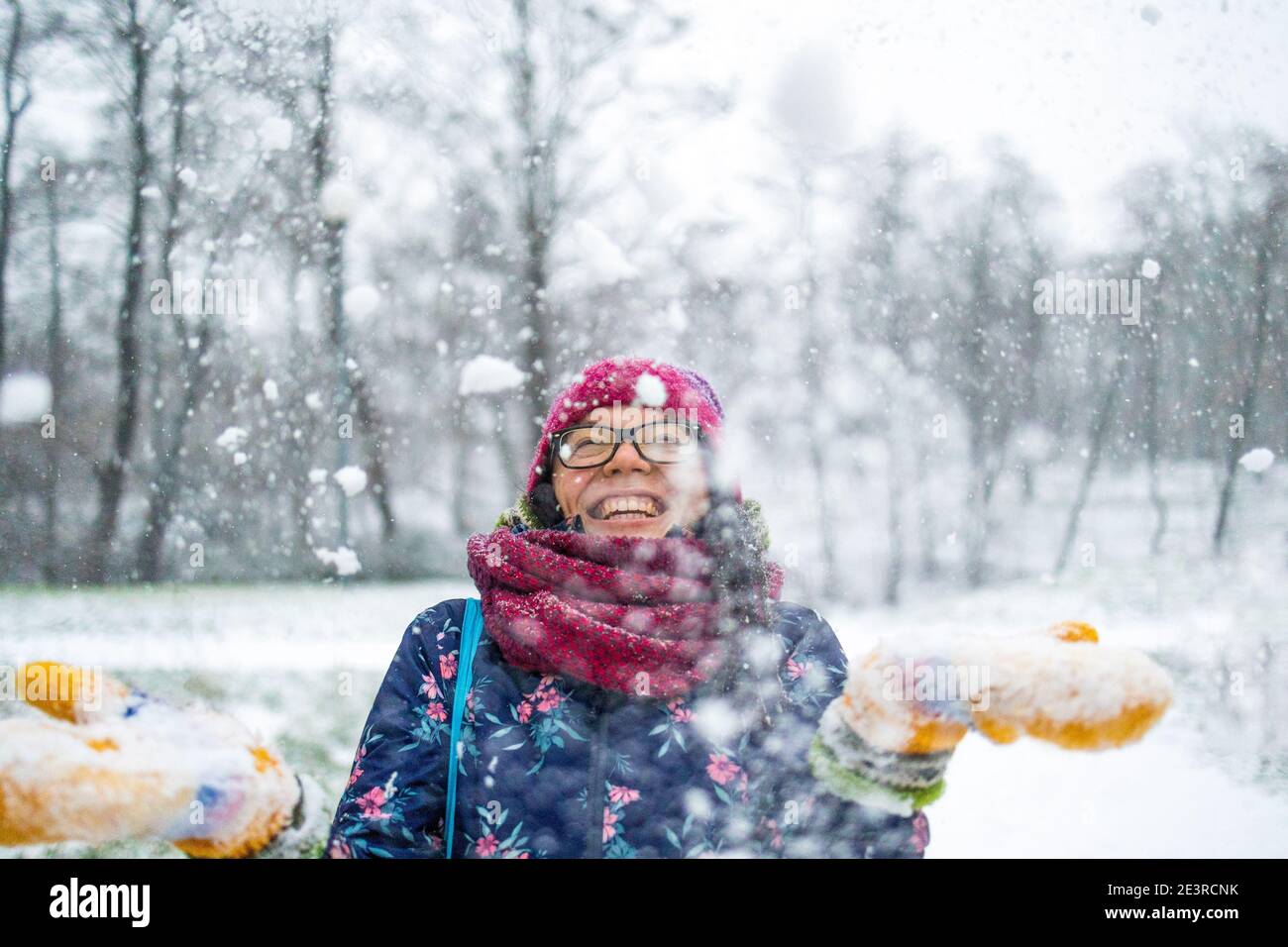 Donna che getta la neve nell'aria e che gode di un freddo giorno invernale Foto Stock