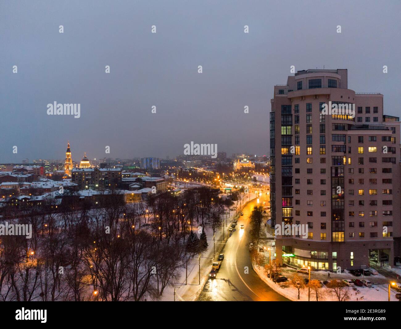 Inverno sera vista aerea sulla strada nevosa del centro con alto edificio a più piani a Kharkiv, Ucraina. Città urbana colori wintery Foto Stock