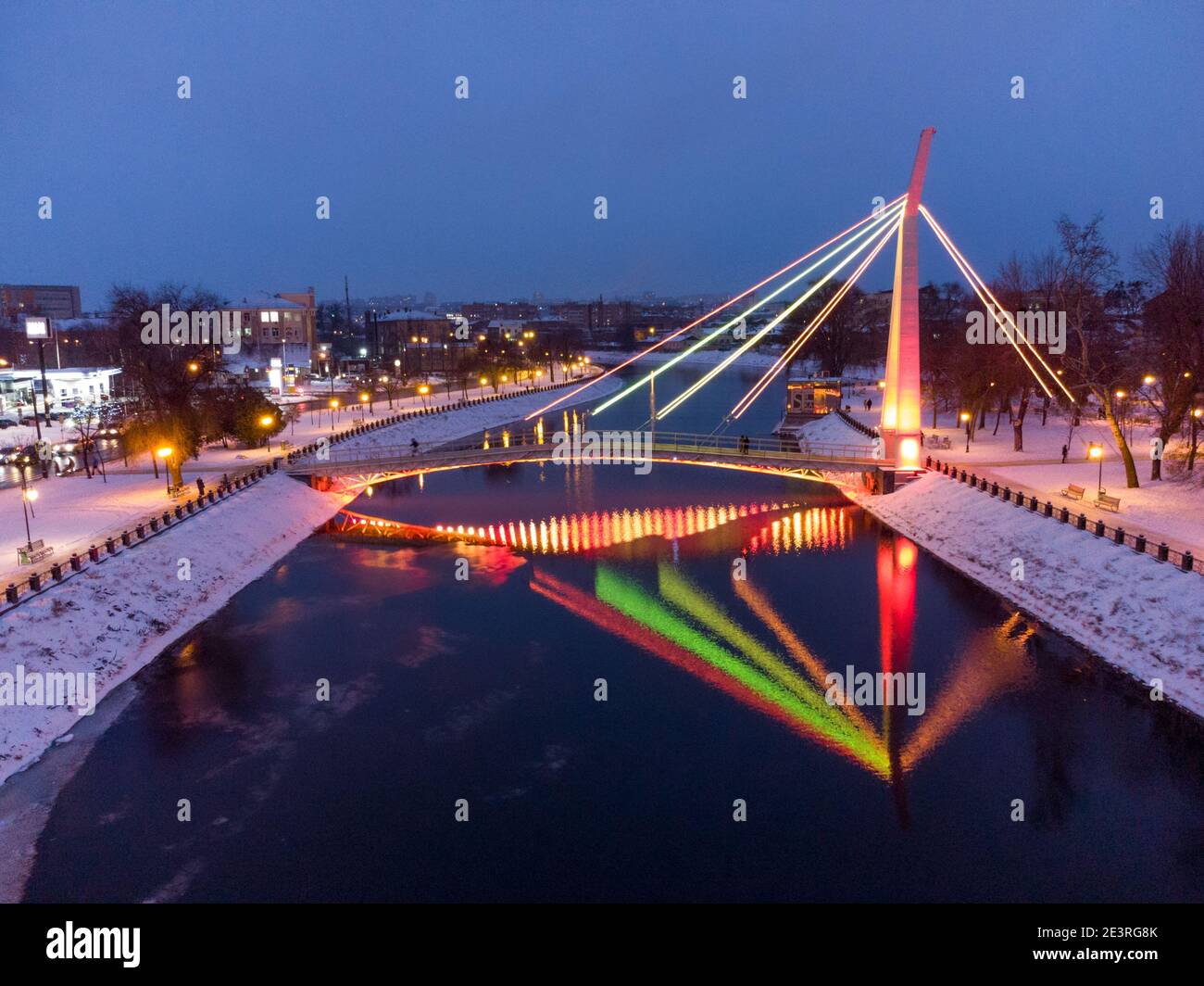 Ponte (Mist Zakokhanykh) attraverso il fiume in illuminato Skver Strilka nel centro di Kharkiv. Foto colorata della serata aerea invernale Foto Stock