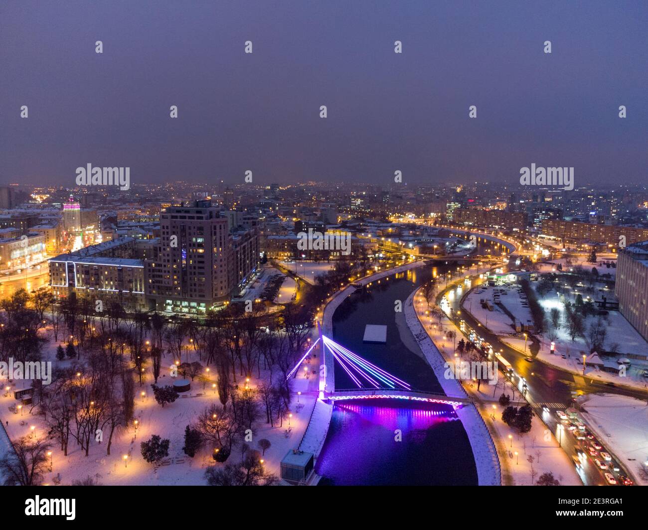 Ponte (Mist Zakokhanykh) attraverso il fiume in Skver Strilka illuminato nel centro città di Kharkiv paesaggio di notte. Foto colorata della serata aerea invernale Foto Stock