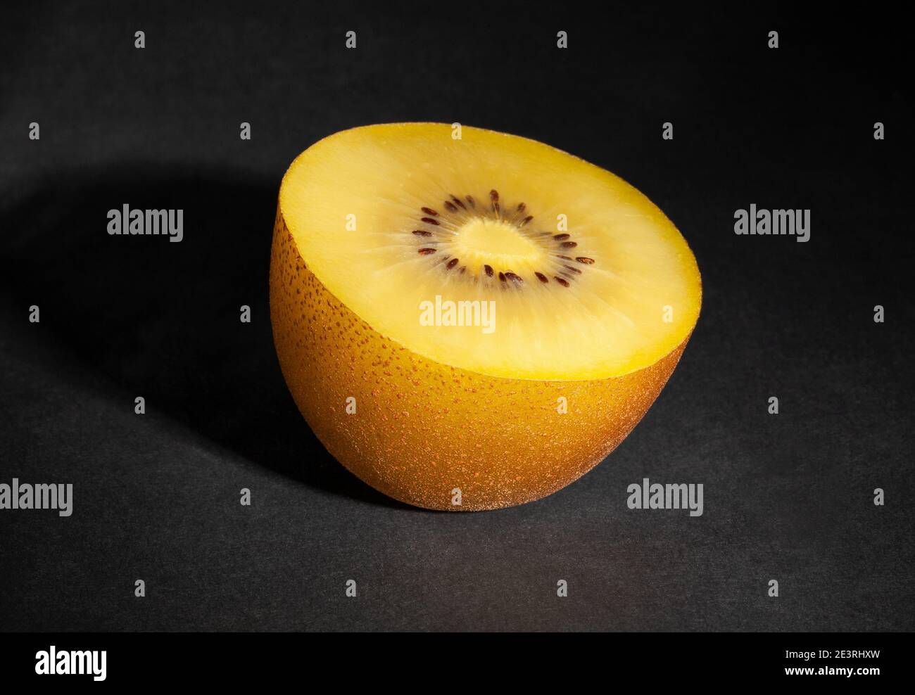 kiwi dorato a fette su sfondo nero Foto Stock