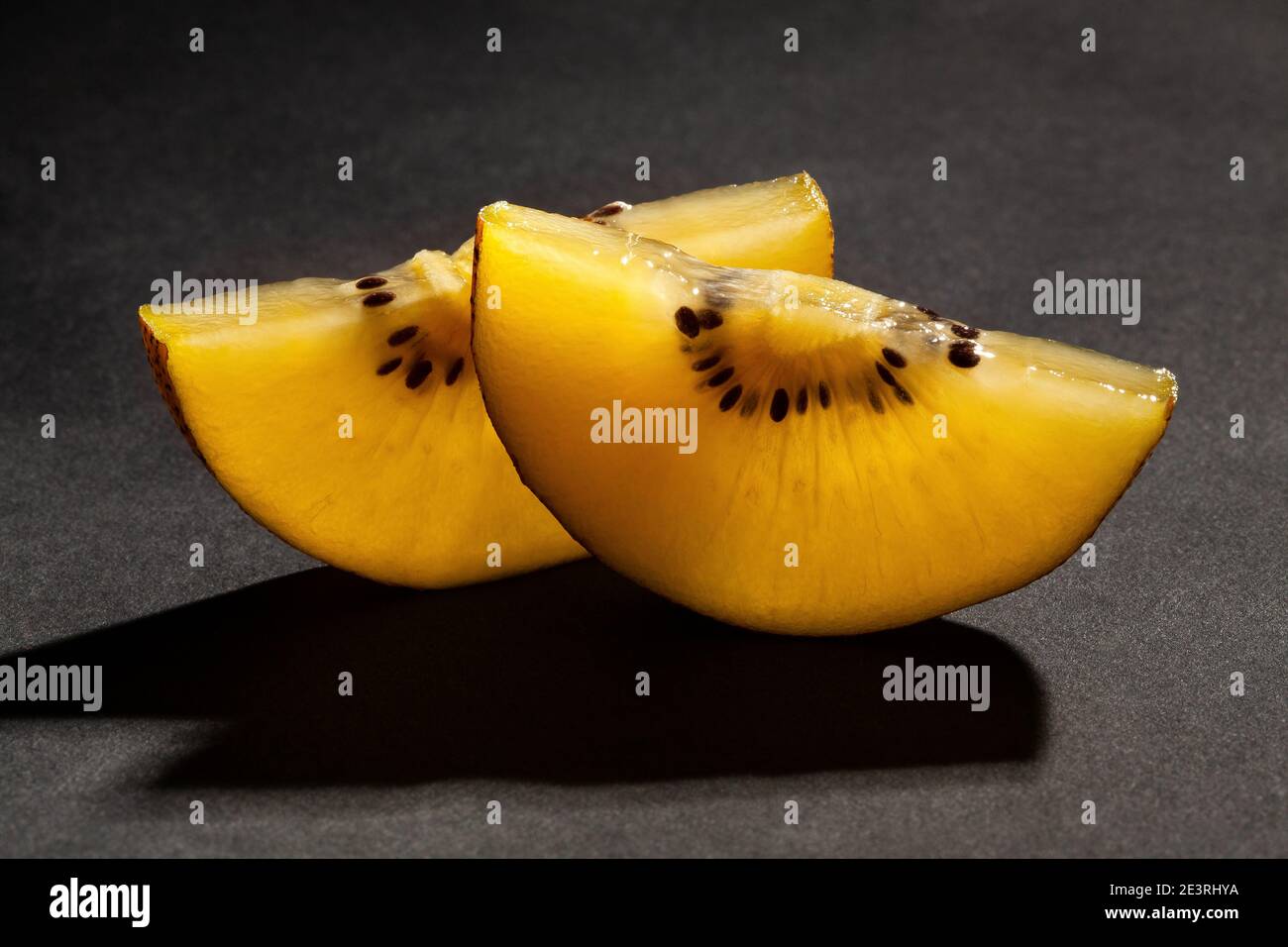 kiwi dorato a fette su sfondo nero Foto Stock