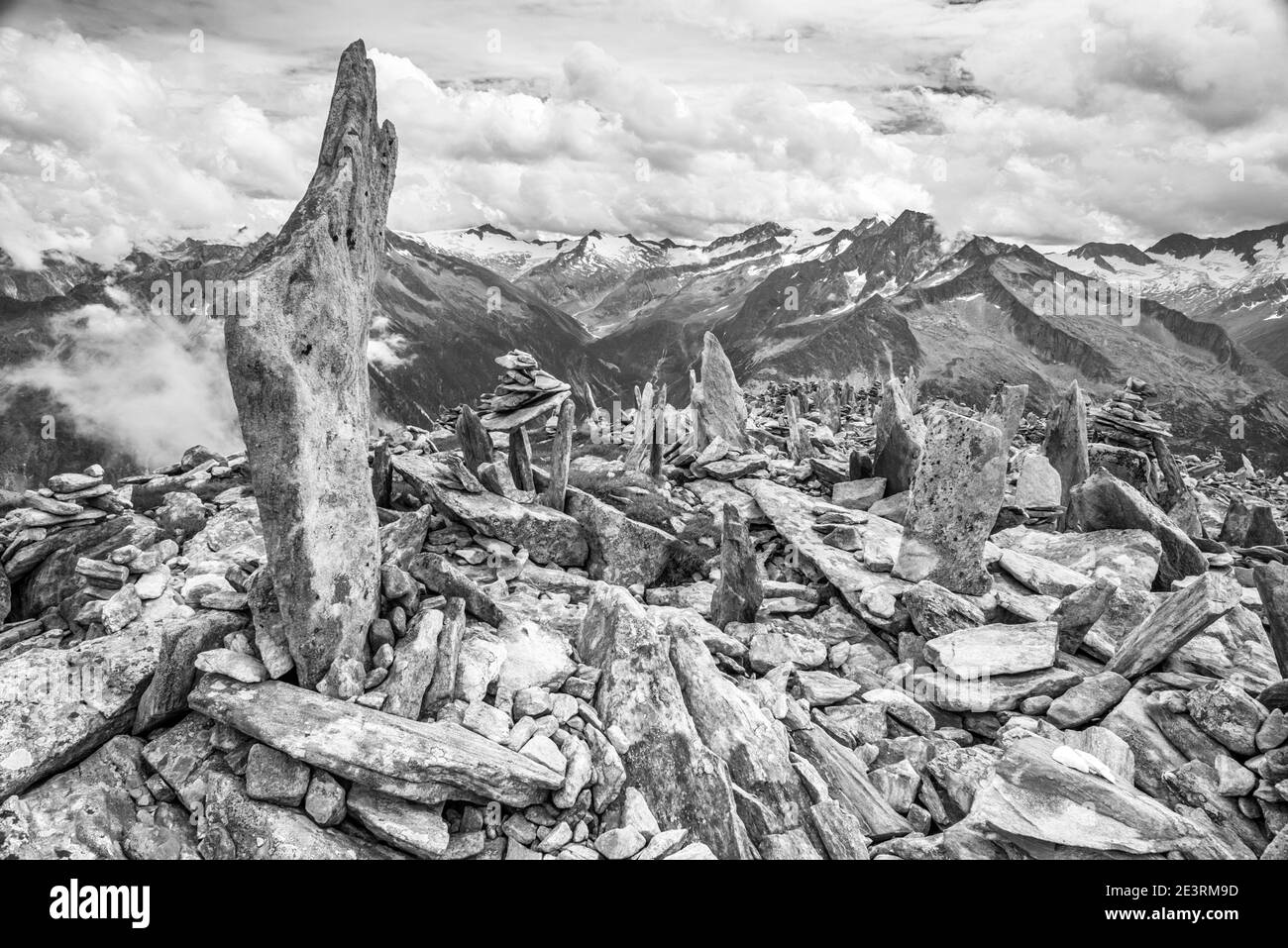 Immagini drammatiche di montagna in monocromo delle montagne delle Alpi Zillertal nel Tirolo austriaco, qui viste guardando attraverso il grande vuoto sopra Schlegeis fino all'Hochfeiler e Grosser Moseler dalla piccola vetta di Peterskopfl sopra il rifugio Friesenberberg Haus, dove ci sono molti cairns pietra costruita da muratori dilettanti di pietra. I cairns, quando sono stati costruiti per la prima volta, sono in ricordo dei molti membri ebrei del Club Alpino tedesco che sono morti durante l'Olocausto della seconda guerra mondiale. Oggi quel memoriale sembra essere perso sui visitatori al piccolo picco del ricordo che vogliono solo aggiungere Foto Stock