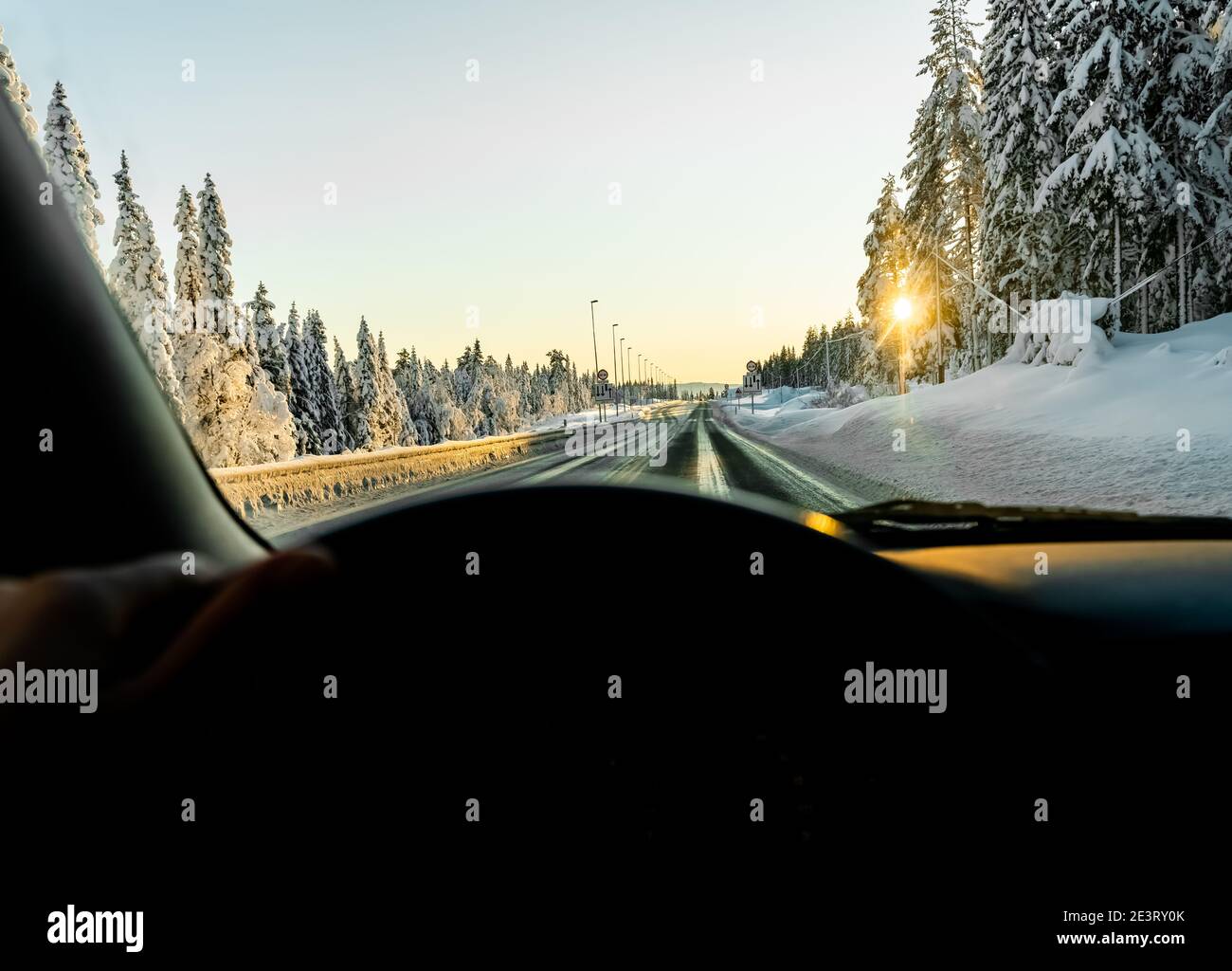 Guida lungo una strada ghiacciata scivolosa in un bosco invernale. Prospettiva del conducente. Foto Stock