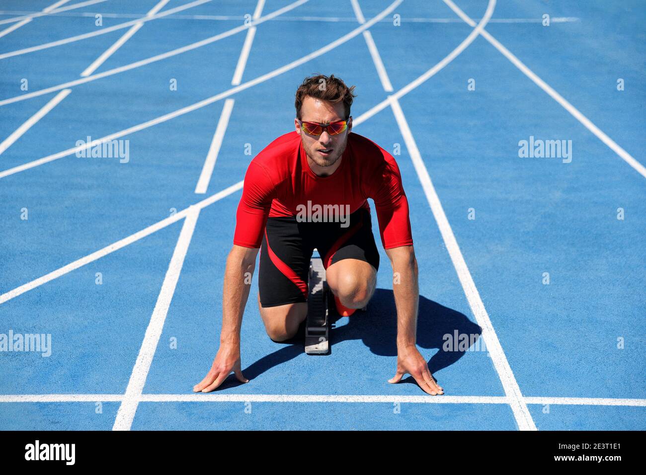 Atleta di runner che inizia a correre all'inizio della pista su piste da corsa blu all'aperto e allo stadio dei fiel. Sport e fitness man running in Foto Stock