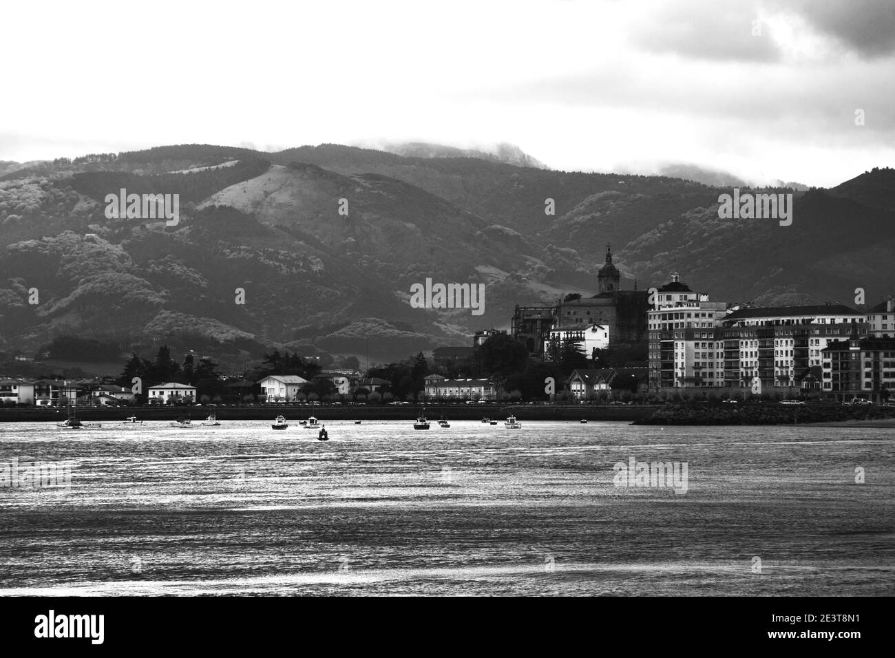 Vista del porto turistico di Hondarribia (Spagna), degli edifici della città e della montagna Jaizkibel sullo sfondo in un giorno nuvoloso di primavera. Foto in bianco e nero. Foto Stock