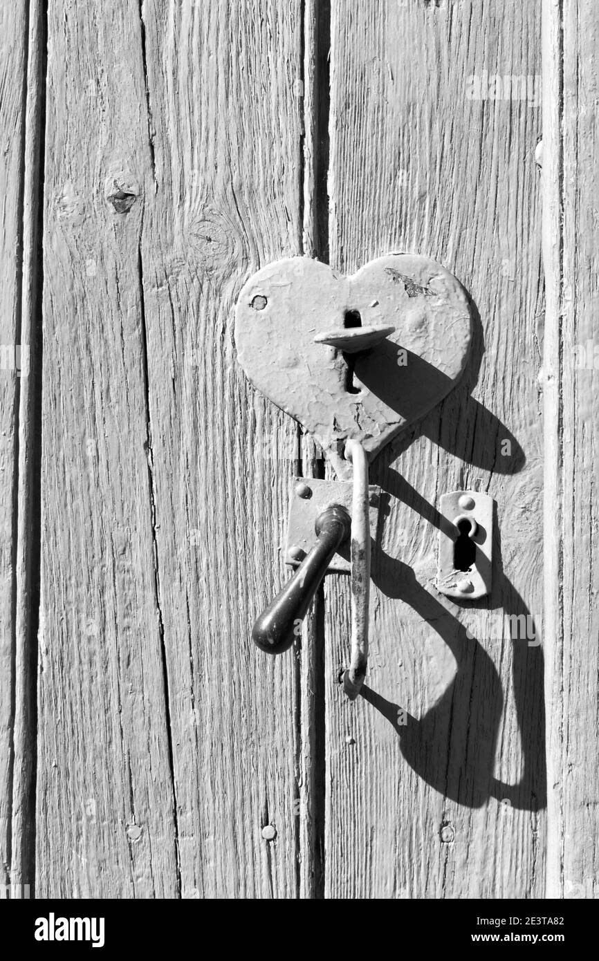 Vecchia porta in legno con serratura a forma di cuore e maniglia. Apri il concetto di cuore. Amore, carità idea. Stile retrò. Sfondo vintage. Bianco nero Foto Stock