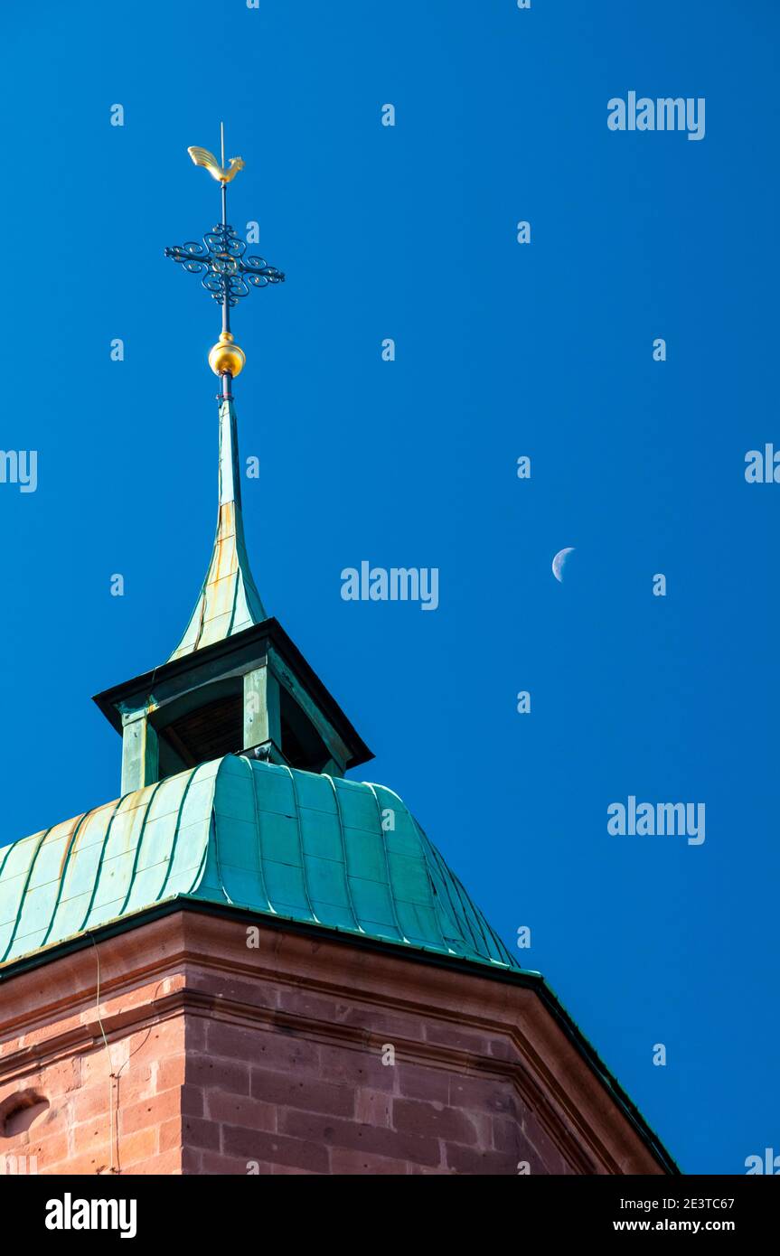 Una luna a mezzaluna diurna dietro la cima dell'orologio torre dell'Evangelische Stadtkirche (Chiesa della città evangelica) ai margini della piazza del mercato Foto Stock
