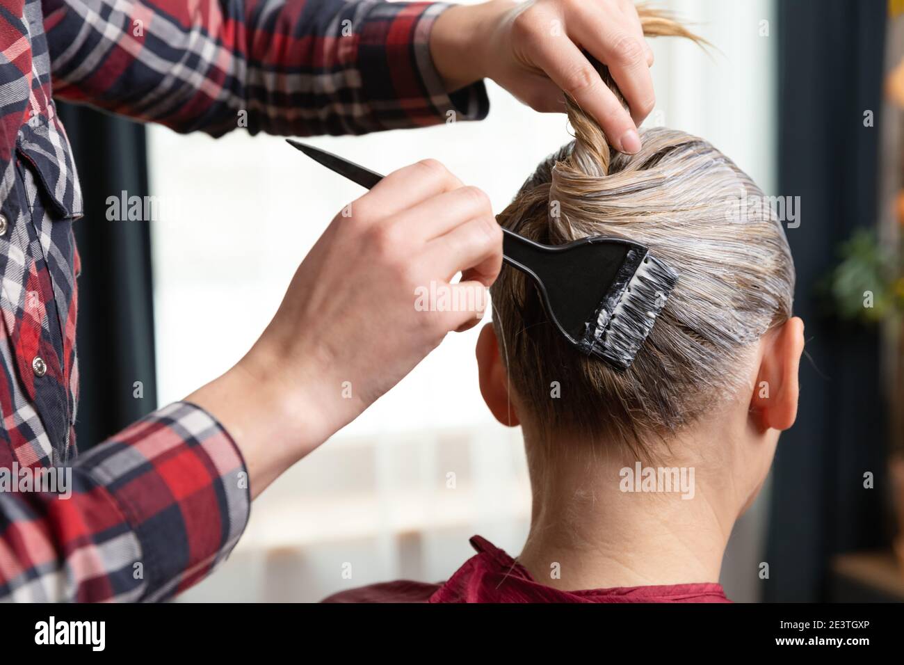 Donne che colorano i capelli ad una donna bionda a casa con un pennello. Rimani a casa. Foto Stock