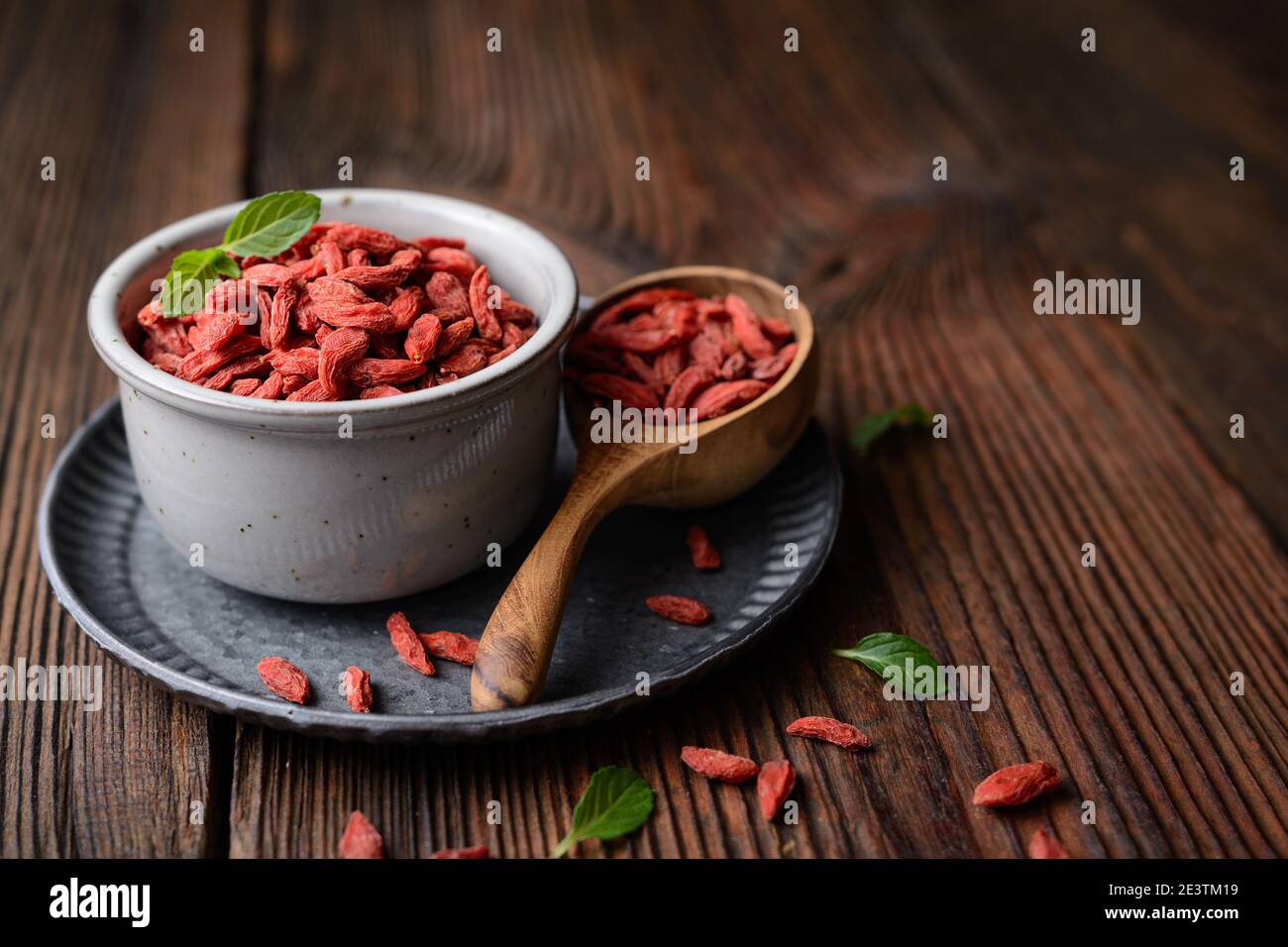 Snack sano ricco di antiossidanti e vitamine per aumentare l'immunità, bacca Goji essiccata in una ciotola e scoop su fondo rustico di legno con copia spac Foto Stock