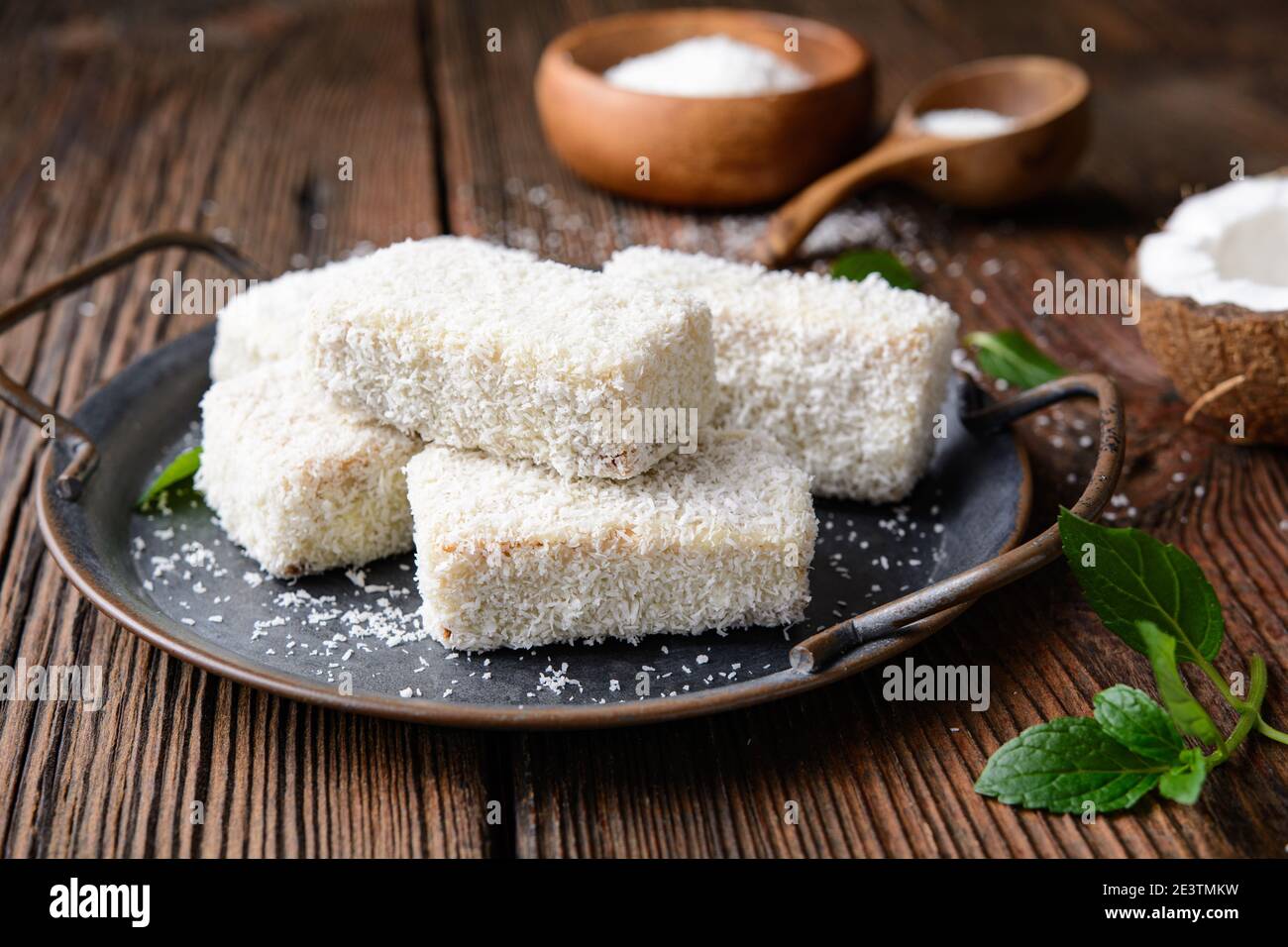 Delizioso dessert dolce, Lamingtons cioccolato bianco coperto di cocco grattugiato su rustico sfondo di legno Foto Stock