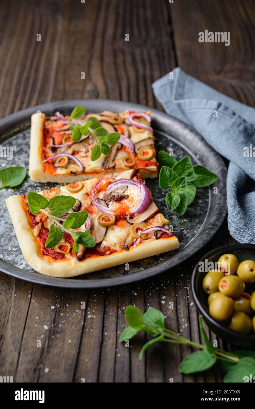 Pizza di funghi Shiitake sana e fatta in casa con fette di olive verdi, formaggio, cipolla rossa e origano su rustico fondo di legno Foto Stock