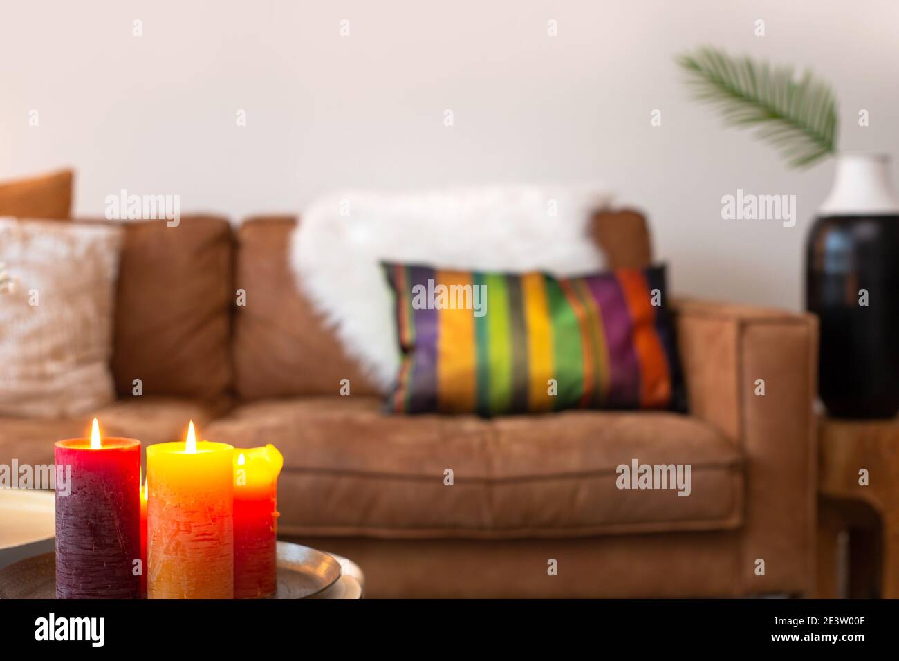 soggiorno interno luminoso e colorato con divano sullo sfondo con candele bruciate su sfondo sfocato, arredamento moderno stile, spazio copia per Foto Stock