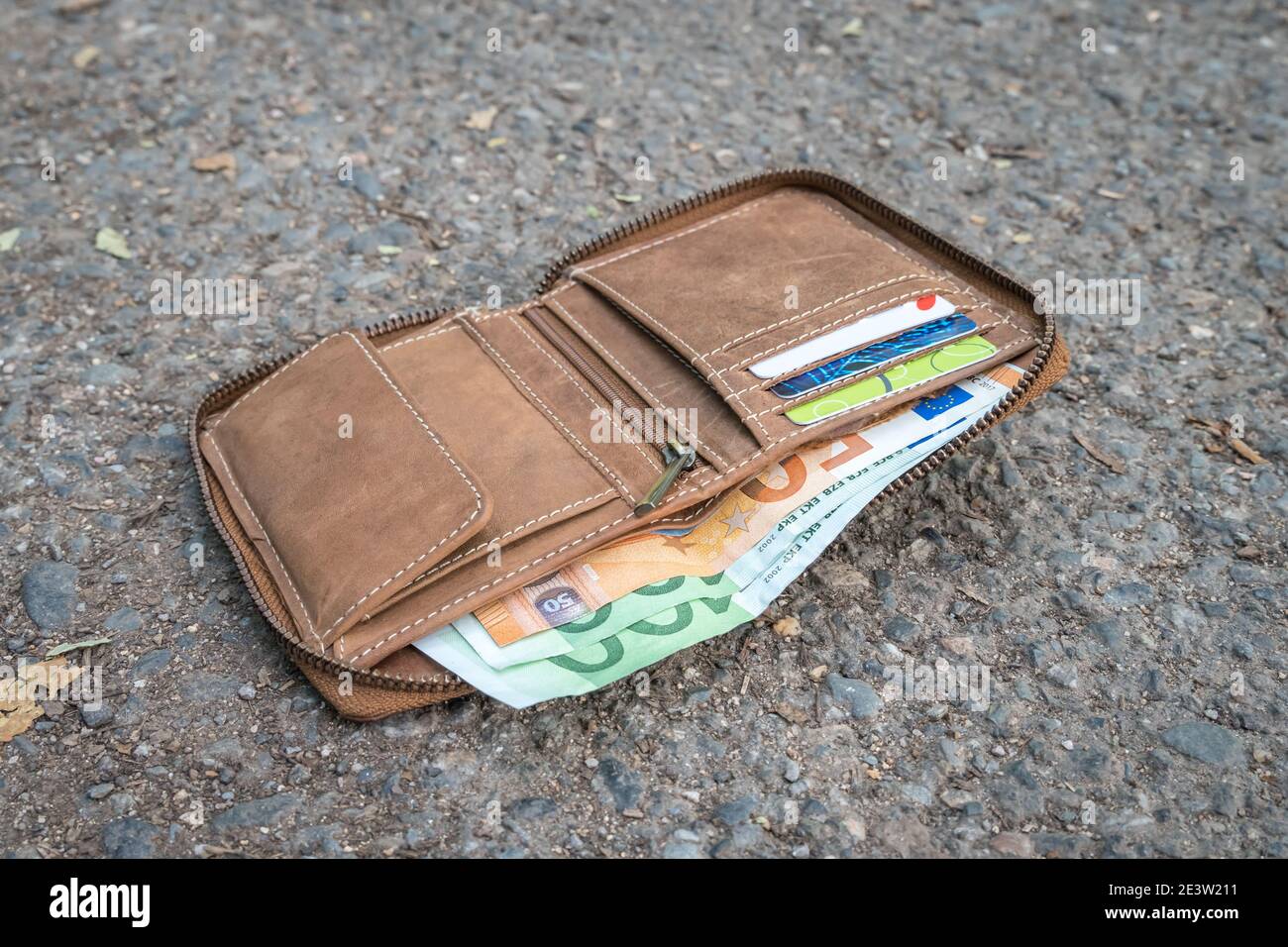Portafoglio in pelle perso con soldi a terra sulla strada Foto stock - Alamy
