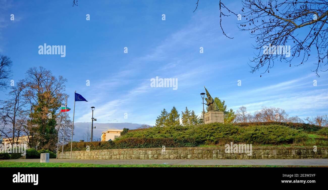 Monumento ai liberatori a Kardzhali, Bulgaria, in un parco con bandiere UE, Bulgaria. Statua su erba verde, cielo blu e sfondo di montagna. Foto Stock