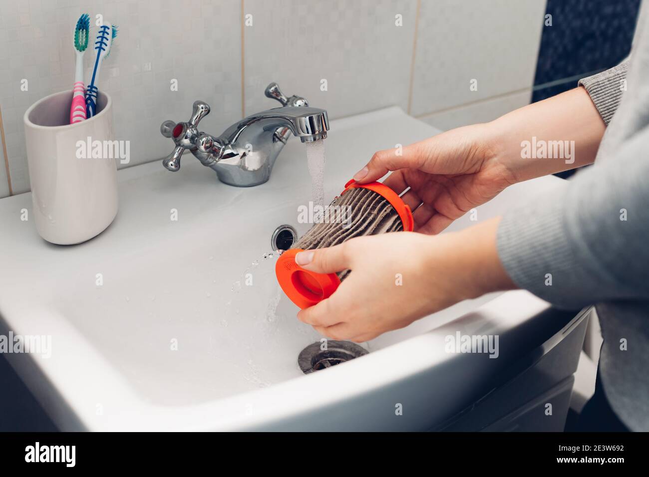 Pulizia del filtro dell'aspirapolvere. Donna che lava il filtro sporco con  acqua nel lavandino del bagno a casa. Hosehold chores Foto stock - Alamy