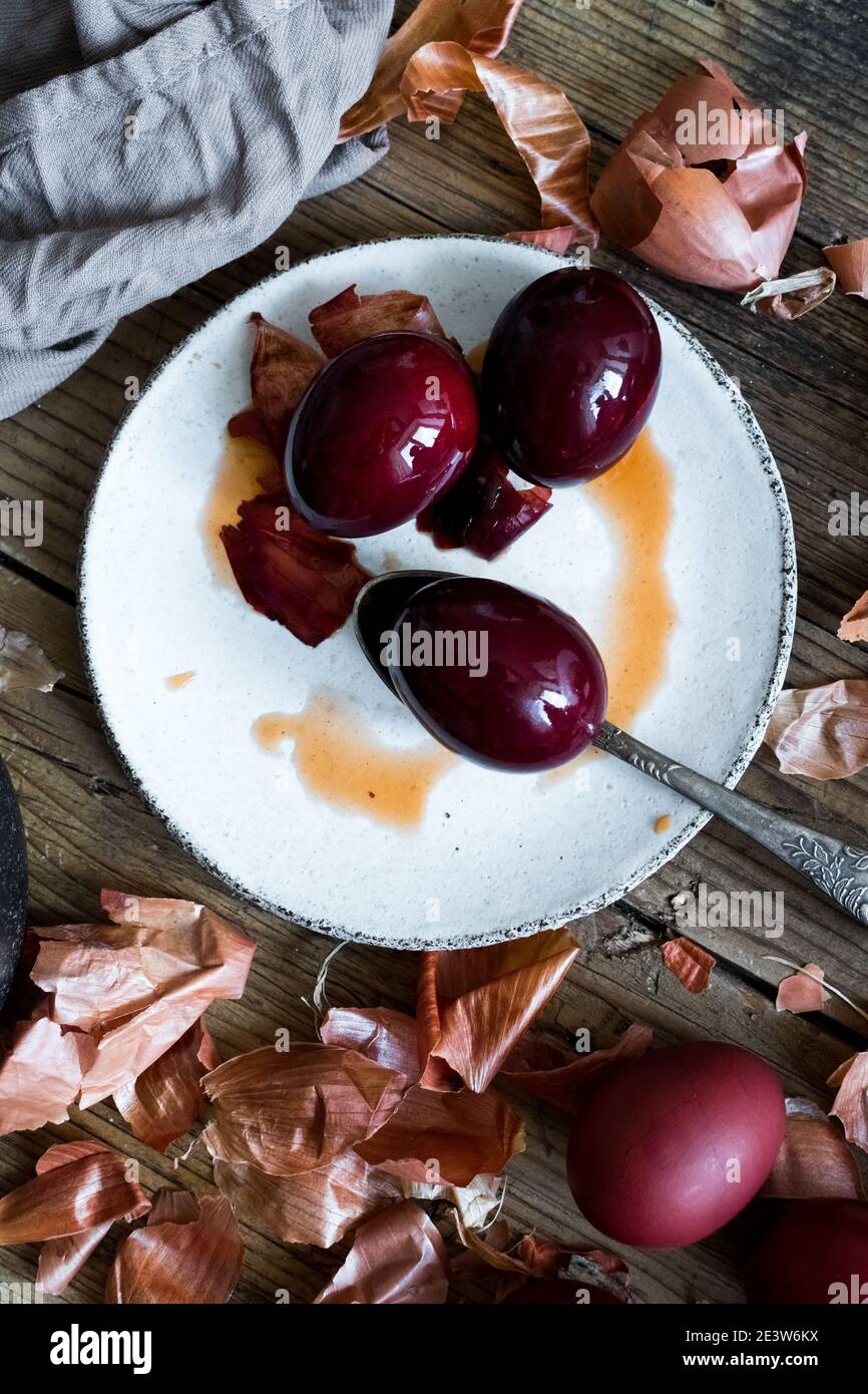 Uova di Pasqua tinti dipinte con cipolla colorante naturale su sfondo rustico in legno. Processo di tintura delle uova con vernici naturali per Pasqua. Ecologico naturale Foto Stock